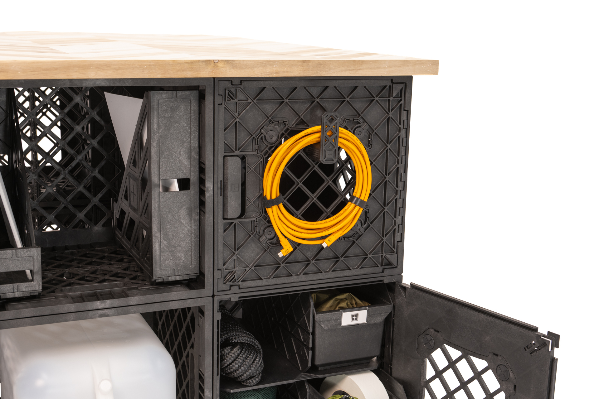 CrateShot Bench Exterior Cord Storage A detail view of the CrateShot Bench showing a coiled extension cord stored on the exterior crate grid, with open compartments and pull-out bins used for organized gear storage.