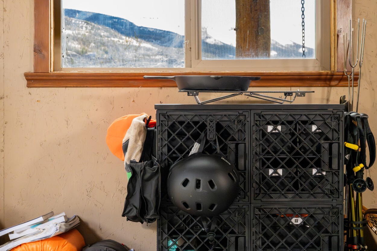 UbeCube modular crate tower used as an outdoor gear station with helmets, trekking poles, cookware, and camping equipment stored together.