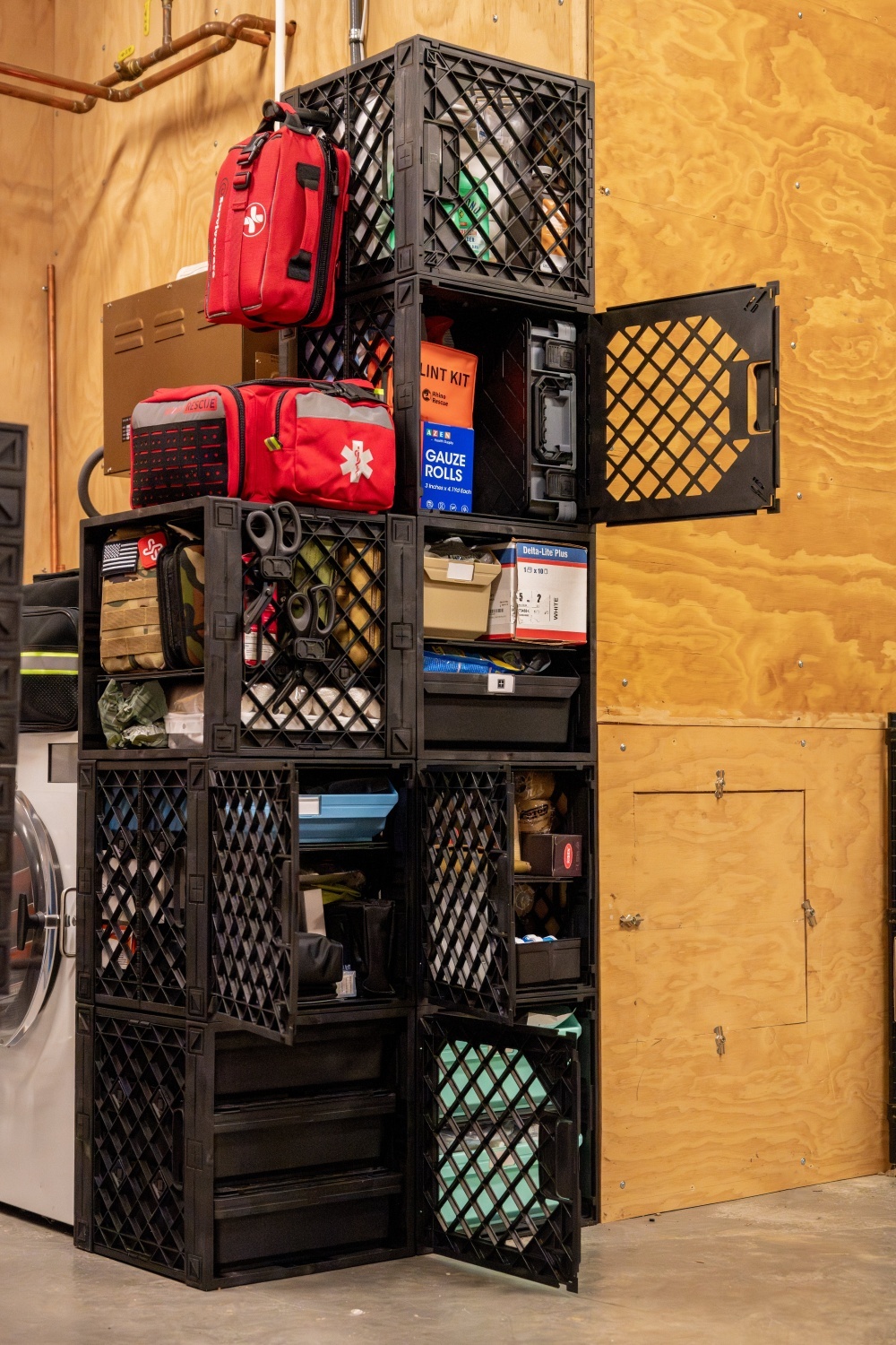 UbeCube&trade; modular prepper storage wall with first aid bags, emergency supplies, tools, trays, and connected crates in a garage setup.