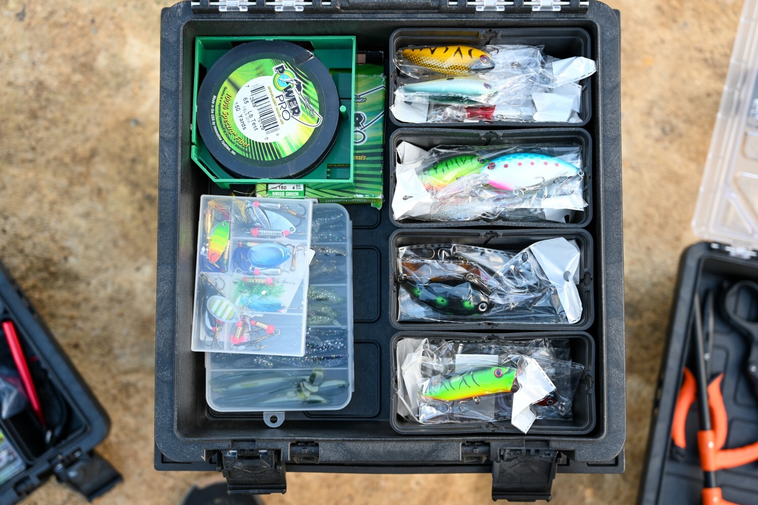 Open BaseBox tackle organizer filled with fishing line, lures, soft plastics, and divided tackle bins.