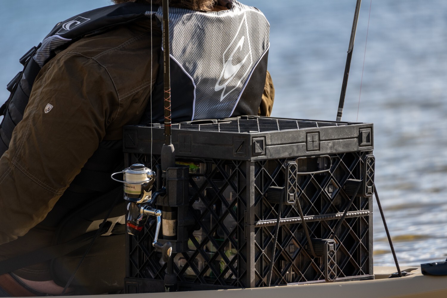 Rear view of a black PaddleOn kayak crate with exterior fishing rod storage and bungee-secured gear.