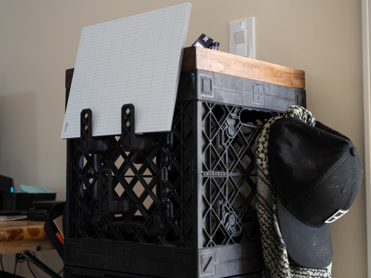 Vertical modular crate bookshelf storing college books with quarter-turn hook attachments for bags and everyday gear